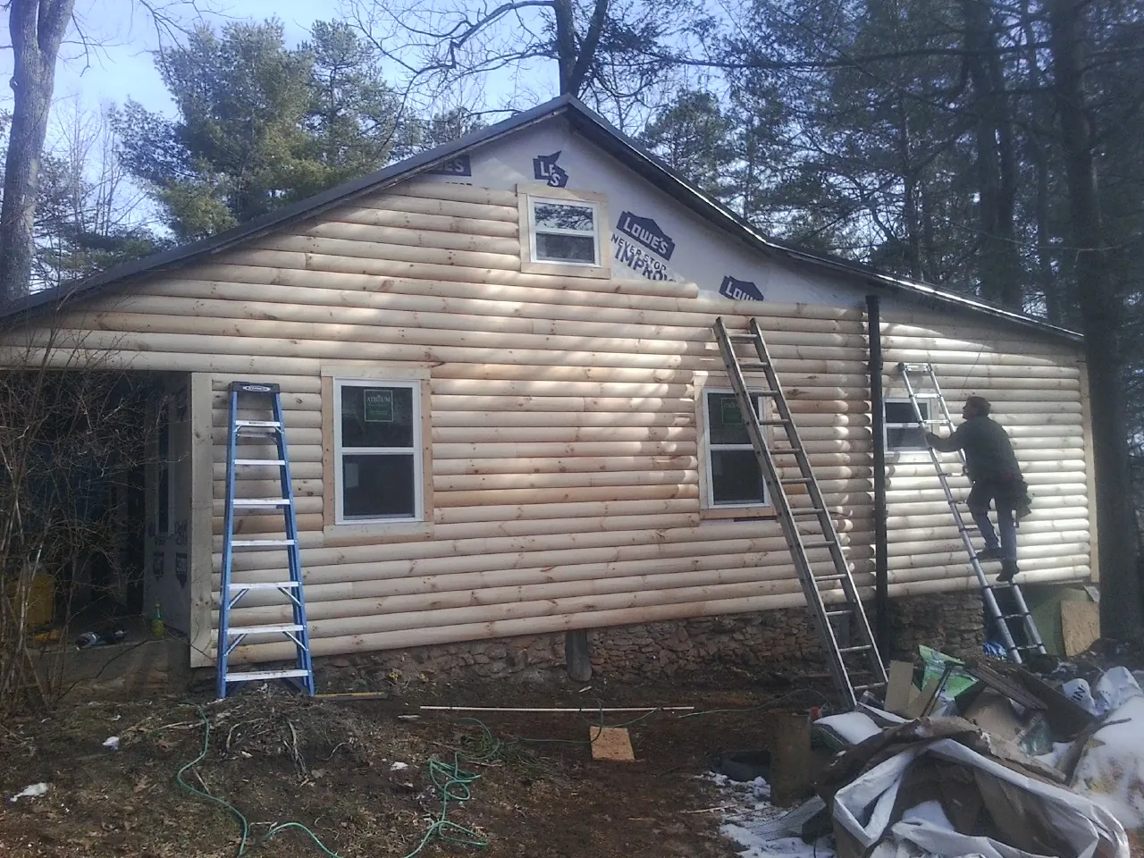 Ladders set against fresh log siding during an exterior remodel in High Springs