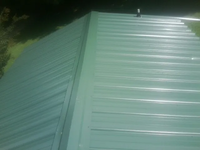 New green metal panels meeting at the ridge of a roof — Flat Roof Repair work by our crew in High Springs