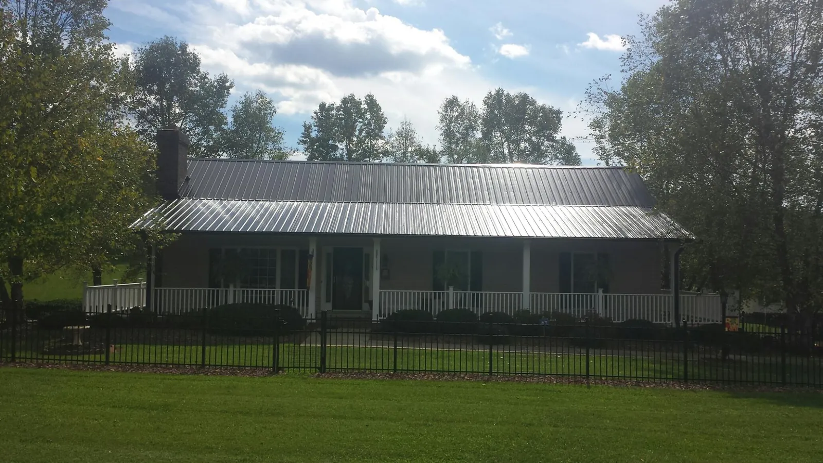 Gray metal roof on a brick ranch with a full width front porch — Gutter Guard Installation work by our crew in High Springs