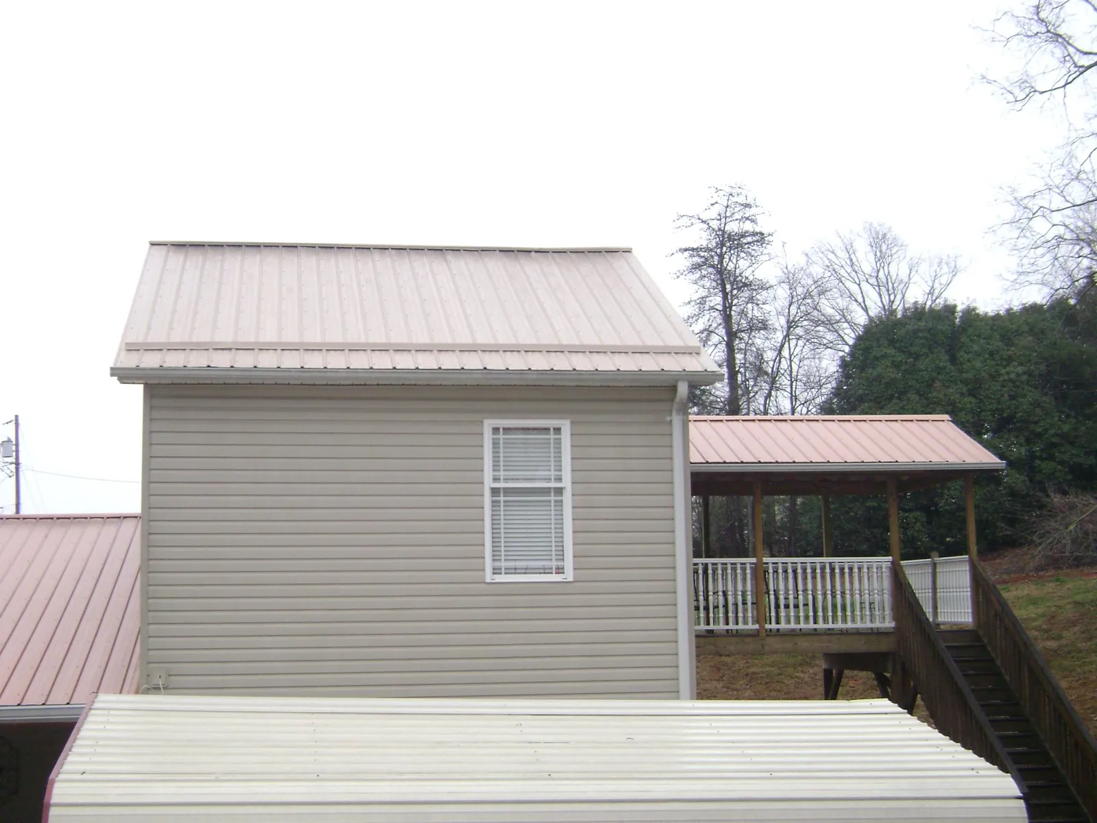Tan metal roofs on a two story addition and attached porch, from a Roof Replacement job in High Springs
