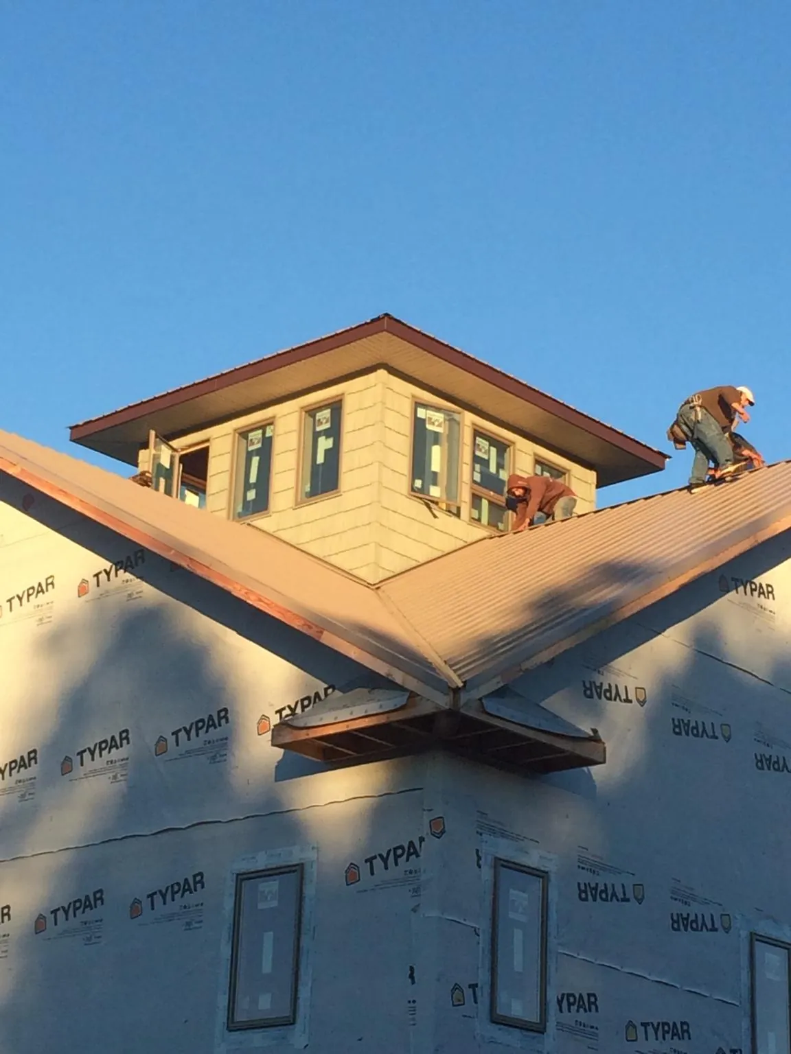 Roofers working around a rooftop cupola on a new metal roof at sunset — Roof Waterproofing in High Springs by Roofing Brothers